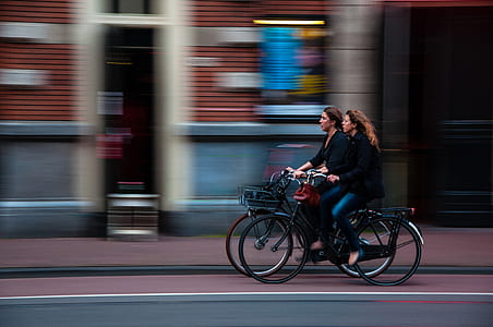 two women riding city bicycles thumbnail