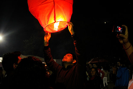 man in b lack jacket holding sky lantern thumbnail
