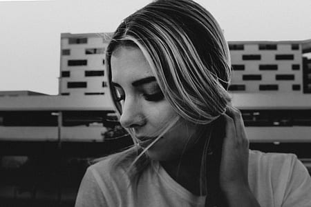 grayscale photo of woman looking down holding her hair thumbnail