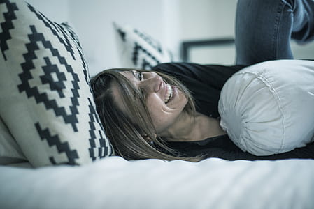 woman lying on bed while laughing thumbnail