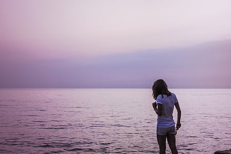 landscape photo of woman standing in front of sea thumbnail