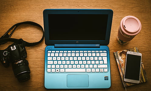 HP laptop computer between Nikon DSLR camera and smartphone thumbnail