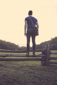 man stands on gray wooden fence during daytime thumbnail