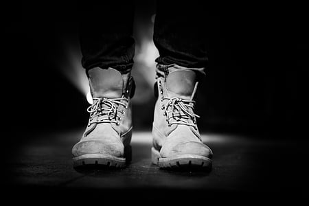 grayscale photography of person wearing pair of boots thumbnail
