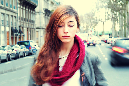 woman closing her eyes while standing in the middle of the road where passing cars go by thumbnail