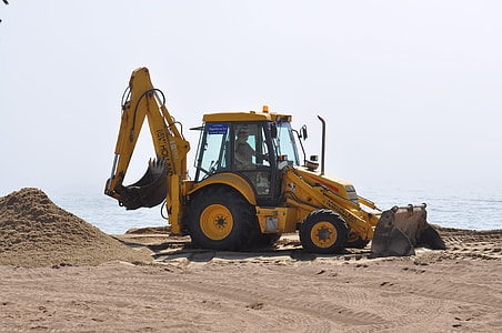 person riding on yellow backhoe near body of water during daytime thumbnail