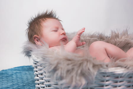 baby sleeping in wicker basket thumbnail