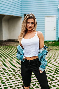 woman wearing white tank top and black bottoms standing in front of blue house thumbnail