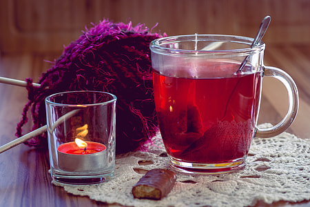 clear glass mug filled with tea beside clear glass tealight holder and purple fleece textile thumbnail