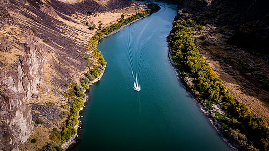Aerial View of Boat on River Between Bushes thumbnail