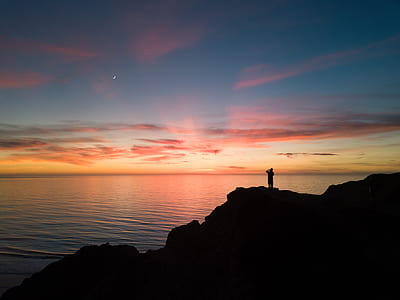 silhouette photo of man standing on cliff thumbnail