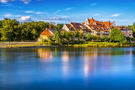 brown and white concrete houses near body of water thumbnail