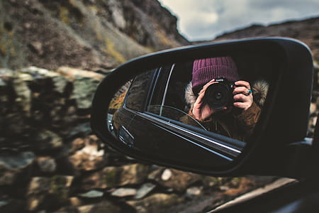 Person Holding Dslr Camera Reflected on Black Framed Wing Mirror thumbnail