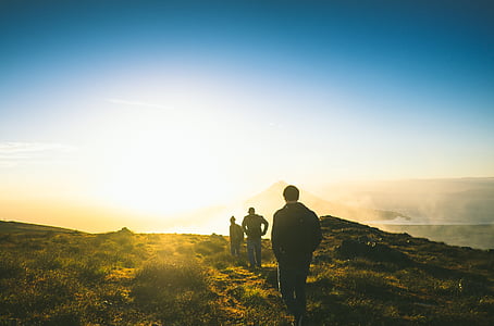 three people walking on mountain under blue sky thumbnail