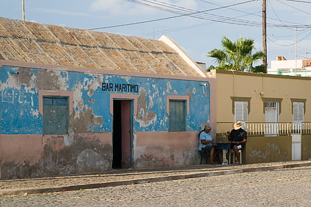 two person sitting beside brown concrete building during daytime thumbnail