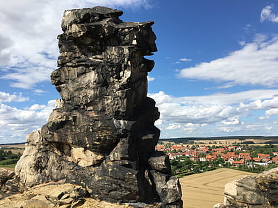 photo of gray rock formation on hill across brown roof house lot during daytime thumbnail