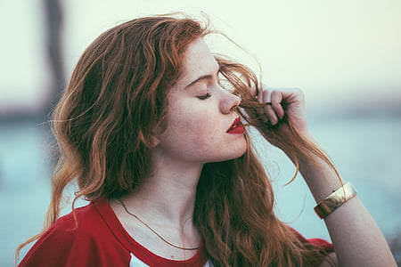 close-up photography of of woman wearing red shirt holding his hair thumbnail