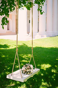 white wooden swing with bouquet of white and pink flowers thumbnail