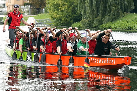 people on red boat rowing paddles thumbnail