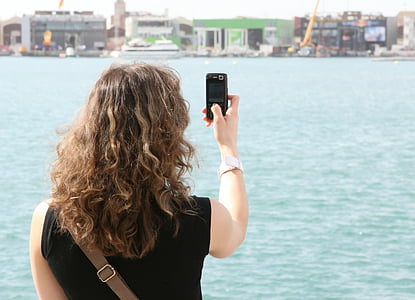 woman taking photo of city and body of water thumbnail