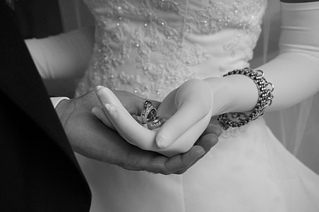 grayscale photography of woman holding wedding rings during wedding thumbnail