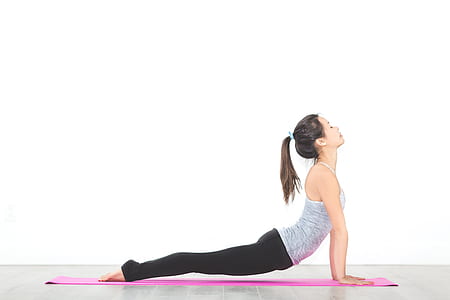 woman wearing grey tank-top doing yoga near white wall thumbnail