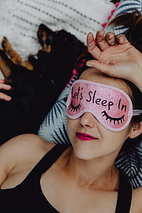 Joyful girl relaxing in bedroom - top view of brunette women in pink sleeping mask thumbnail