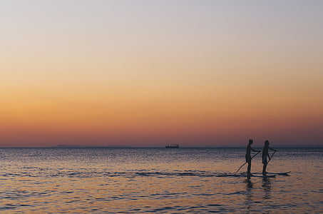 silhouette of two person in middle of water thumbnail