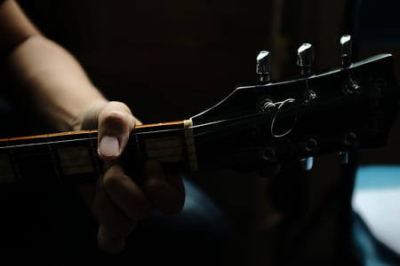 shallow focus photography of person holding guitar neck thumbnail
