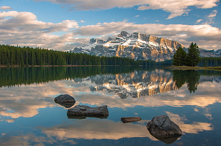 mirror photography of snow capped mountain near green trees during daytime thumbnail