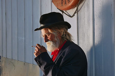man leaning on wall while smoking cigarette thumbnail