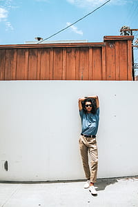 man holding his elbows near white wall thumbnail
