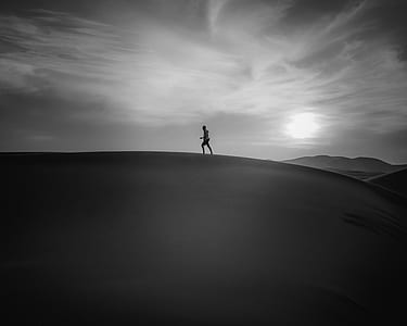 grayscale photography of person standing on sand thumbnail