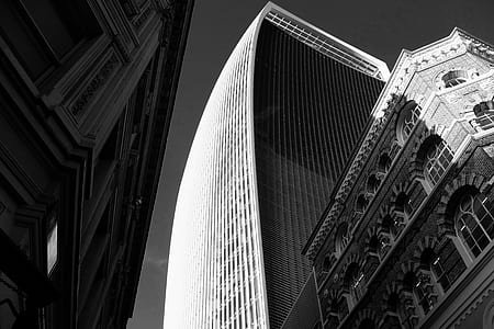 grayscale photo of high rise building under gray sky thumbnail
