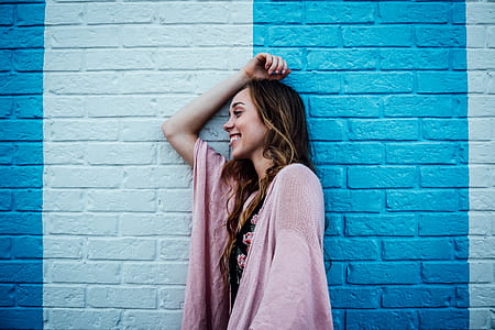 woman taking photo while leaning on blue wall thumbnail