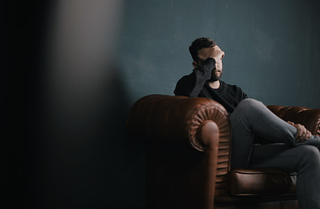 man resting his foot sitting on brown sofa thumbnail