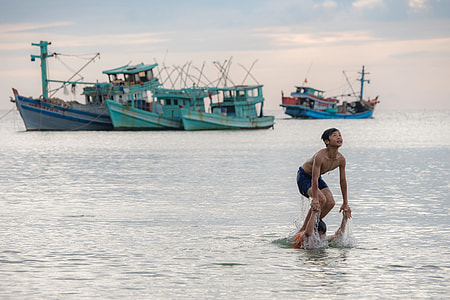 boy standing on another person's shoulder at sea near boats at daytime thumbnail