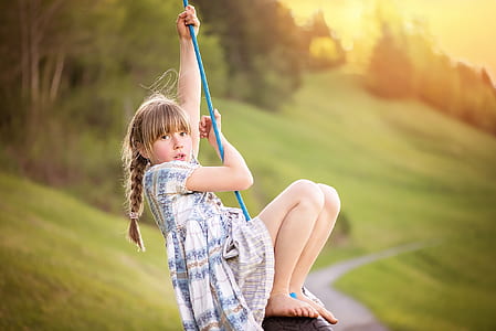 girl sitting on swing holding rope during day thumbnail