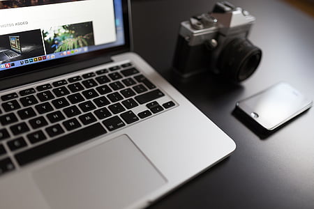 MacBook on table near iPhone and DSLR camera thumbnail