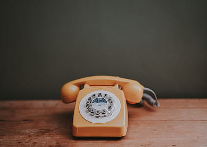 orange rotary phone on top of desk thumbnail