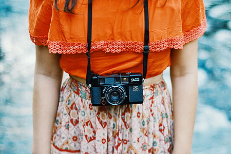 black DSLR camera hanged on person's neck thumbnail