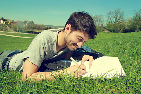 male laying on grass holding pen thumbnail