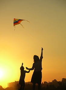 person flying an orange, green, and blue kite thumbnail