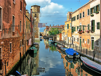 assorted-color boats on canal near houses at daytime thumbnail