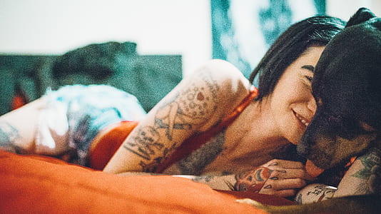 woman lying on bed beside adult mahogany Rottweiler thumbnail