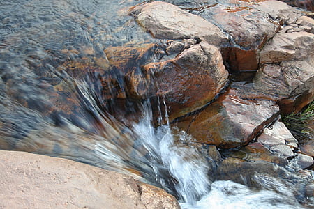 water streaming down on brown rocks thumbnail