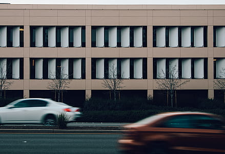 white and red cars passing near brown building thumbnail