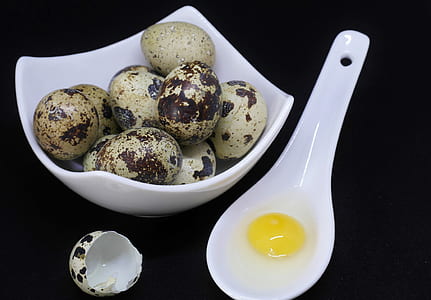 quail eggs on white ceramic bowl beside of spoon with egg yolk thumbnail