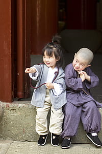 two toddlers sitting on concrete edge thumbnail
