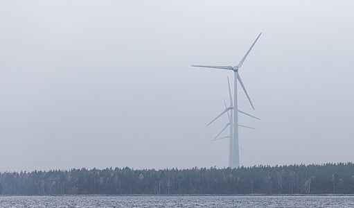 white wind turbines forming line near green trees during daytime thumbnail